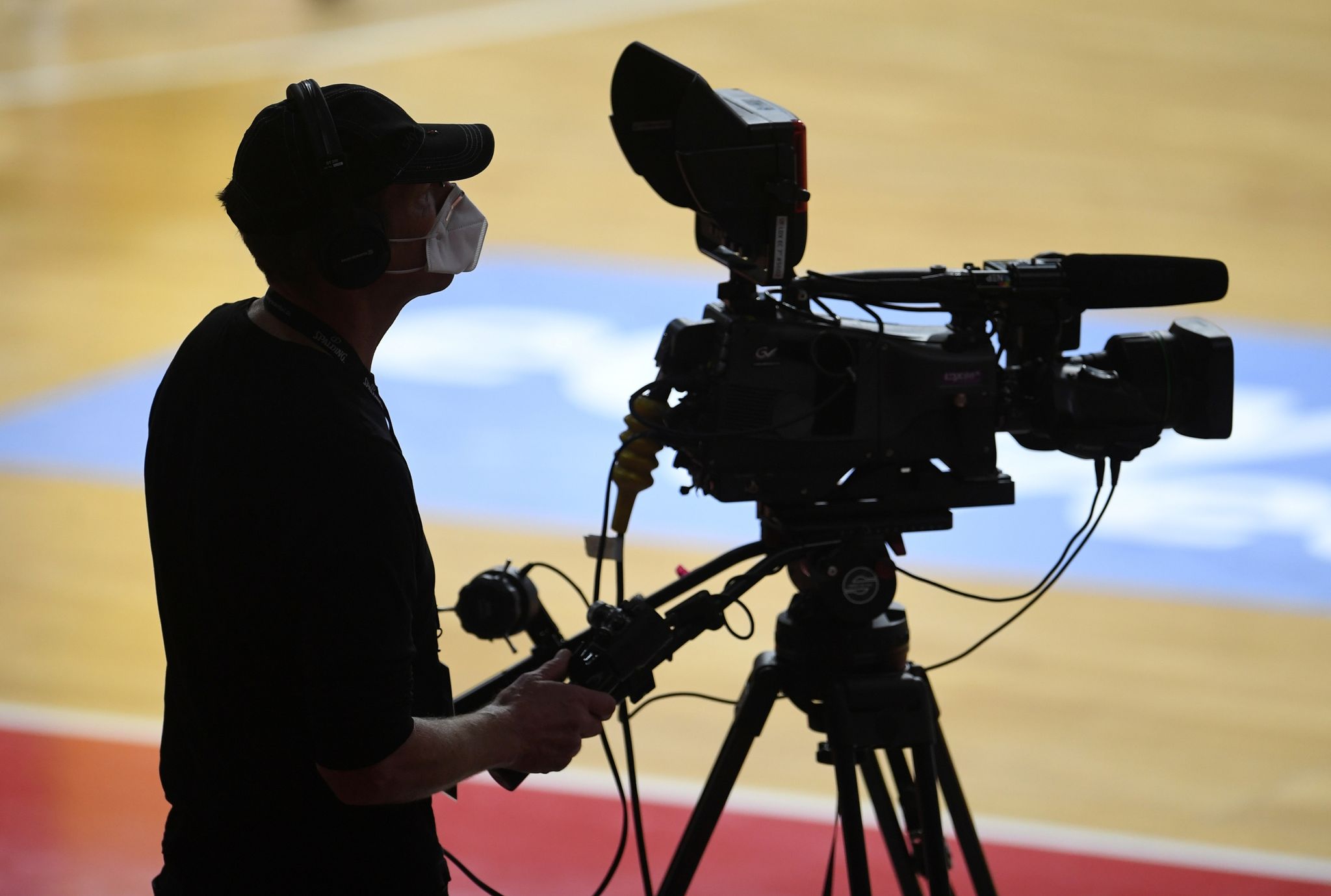 Ein Kameramann steht mit Mundschutz am Rand eines Basketballfeldes. (© Andreas Gebert/Reuters-Pool/dpa)