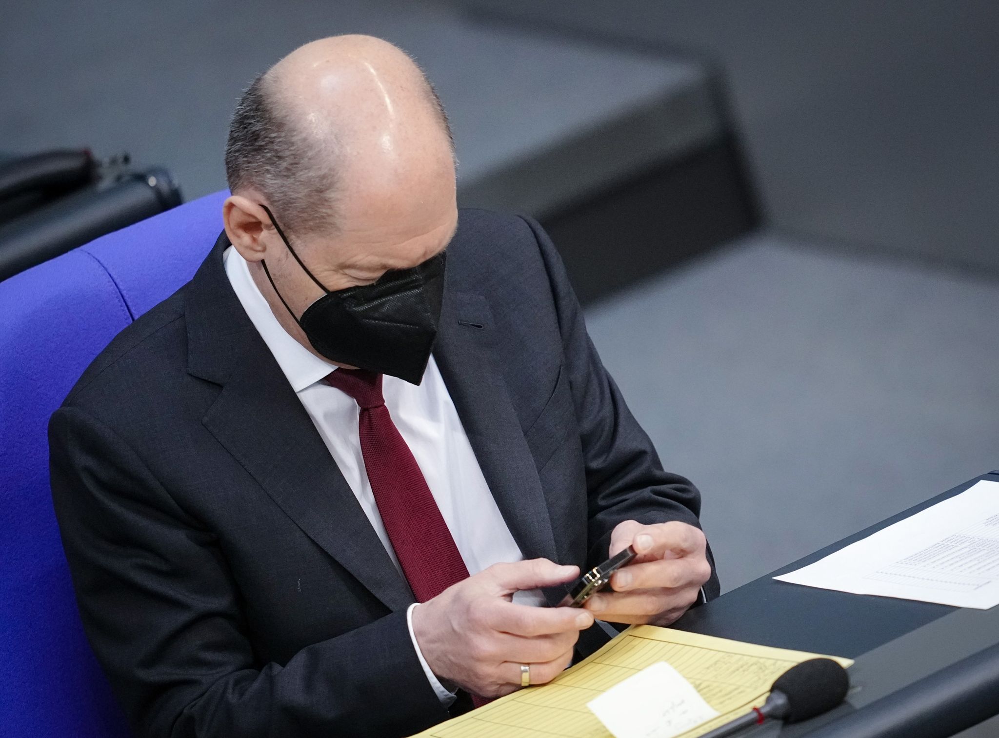 Bundeskanzler Olaf Scholz schaut im Bundestag auf sein Handy (Archivbild). (© Kay Nietfeld/dpa)