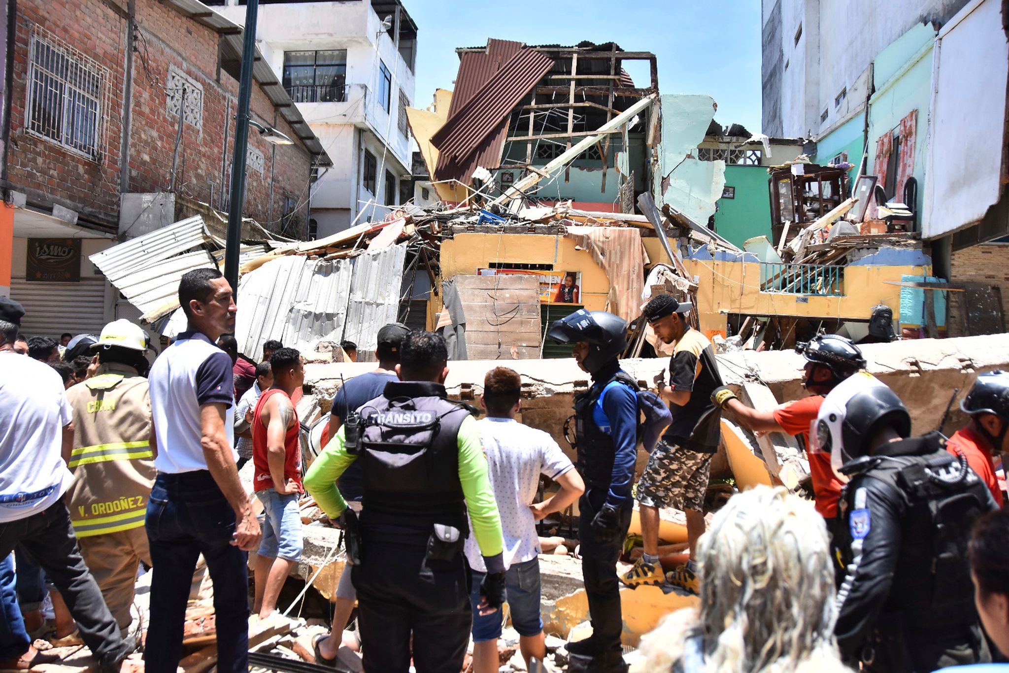 Anwohner und Rettungskräfte stehen vor zerstörten Gebäuden in Machala. (© Jorge Sanchez/AP/dpa)