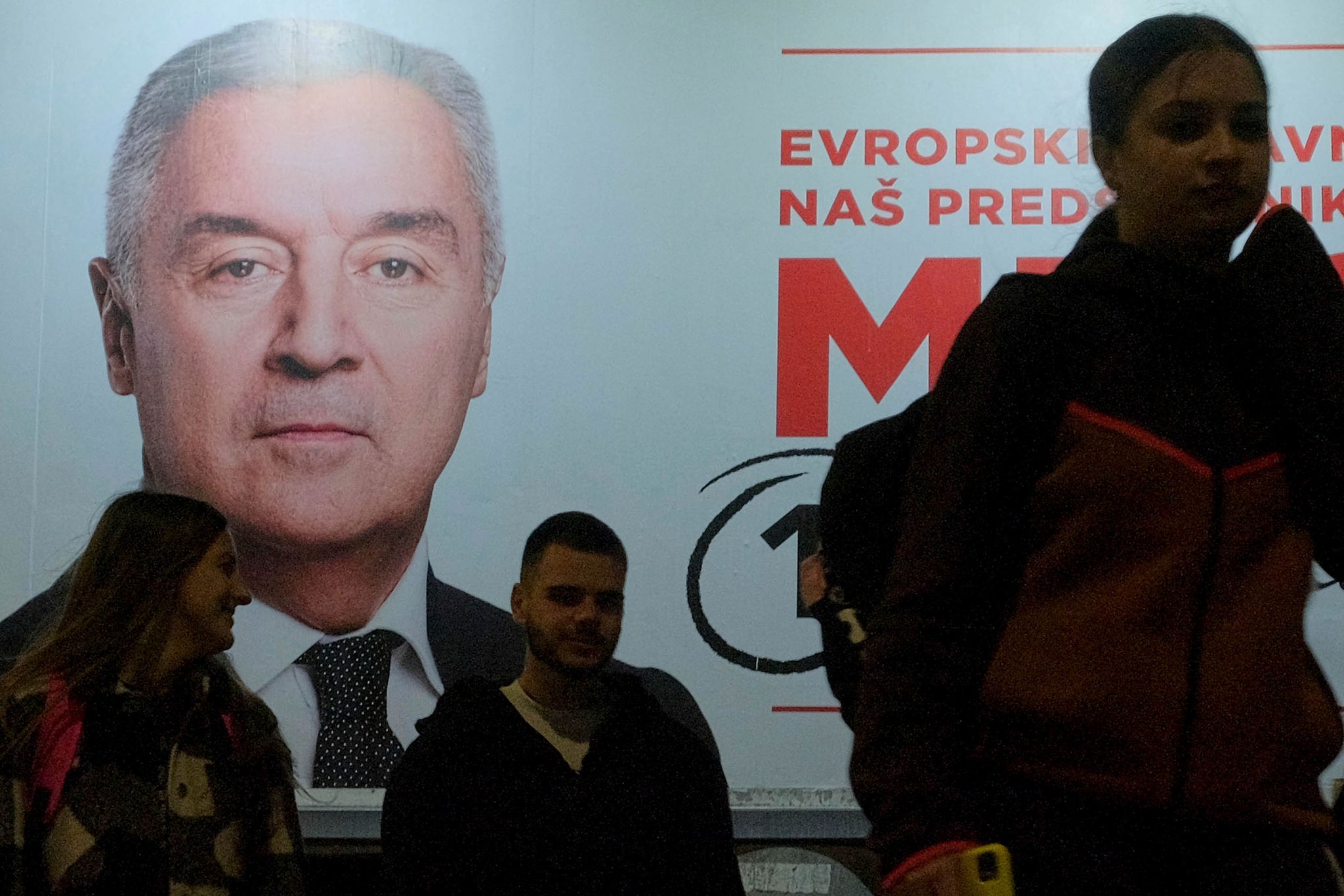 Der Wahlkampf ist zu Ende: Menschen gehen an einem Plakat des pro-westlichen Amtsinhabers Milo Djukanovic vorbei. (© Risto Bozovic/AP/dpa)
