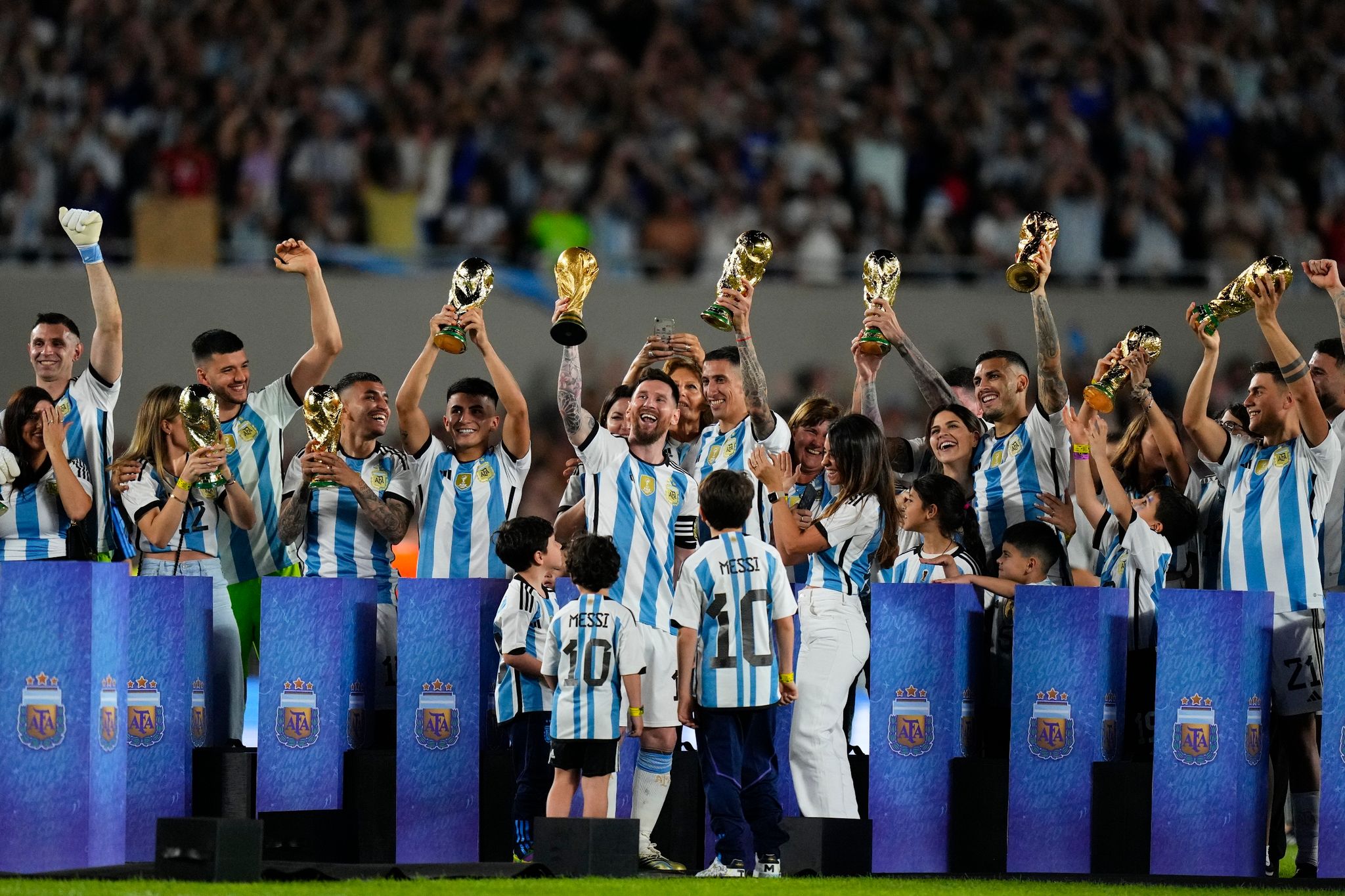 Die argentinische Nationalspieler mit Kopien der Weltmeister-Trophäe während einer Feier für die einheimischen Fans. (© Natacha Pisarenko/AP/dpa)